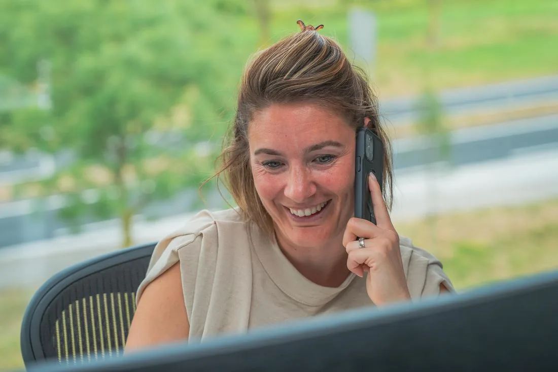 Lachende SOWEDO-collega tijdens een telefoongesprek